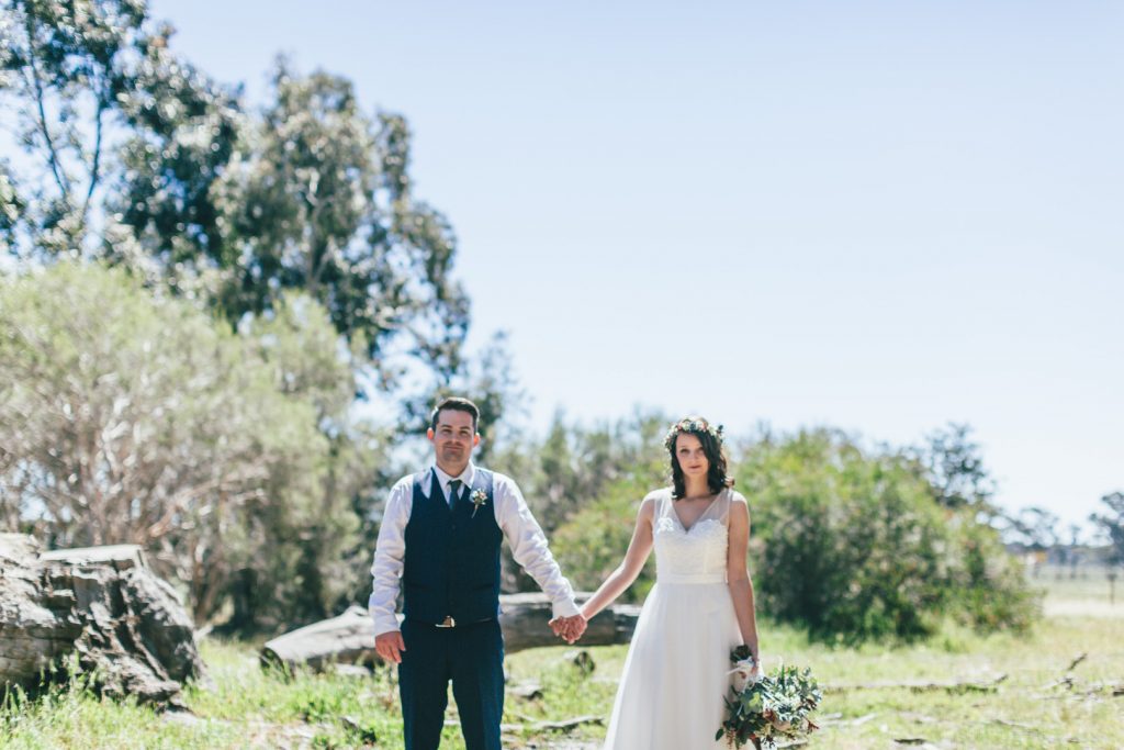 Bride and groom holding hands with Gunyah Valley Retreat background.