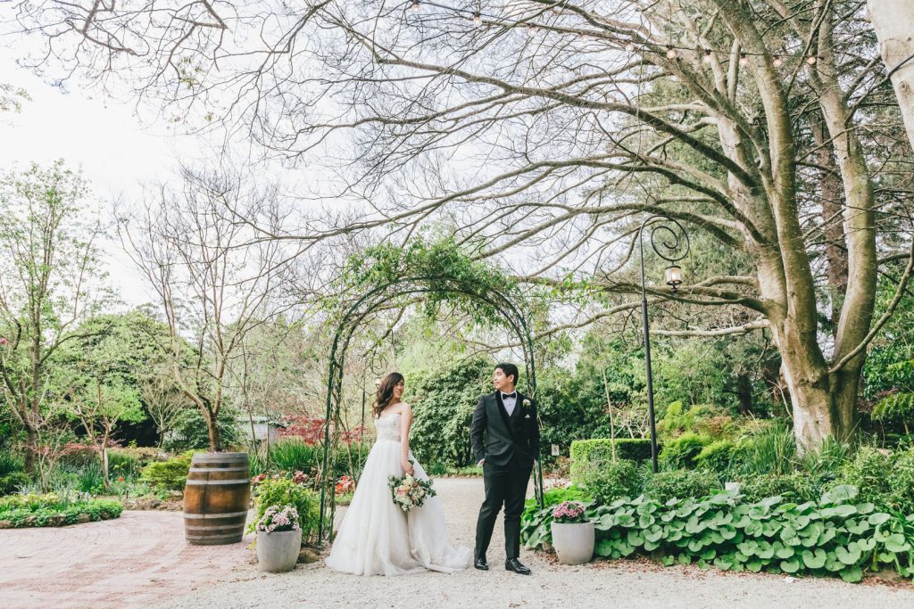 Beautiful photo of bride and groom in front of green arch at Poets Lane wedding.