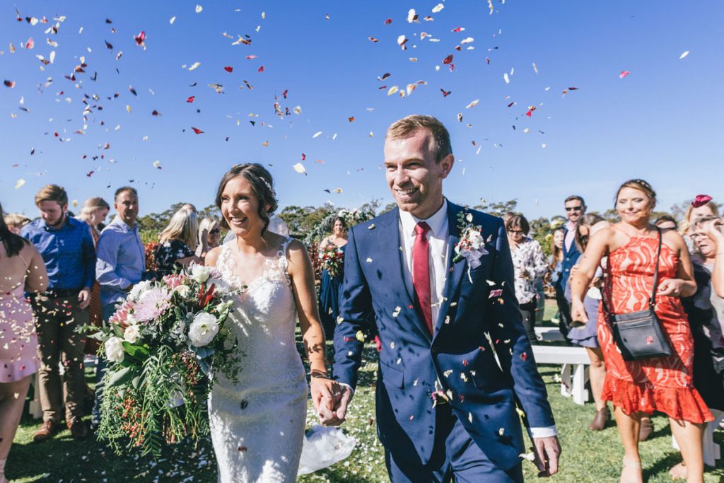 Bride and groom exit ceremony with petals at Norton Estate wedding.