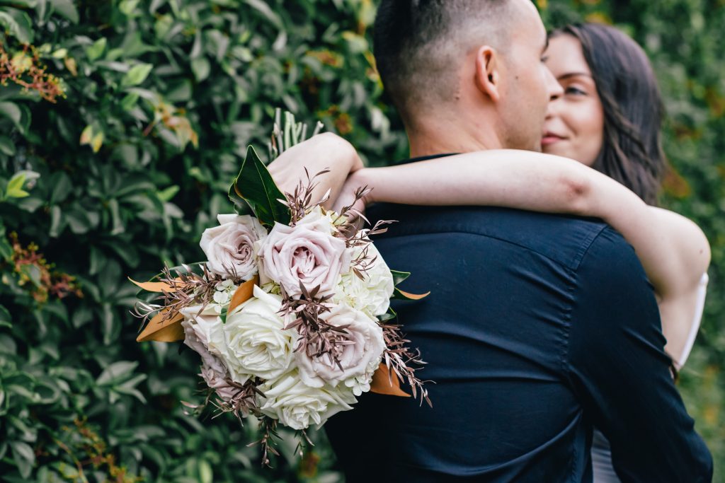 Bride with hands on the groom's shoulders while holding bouquet after Melbourne registry office wedding.
