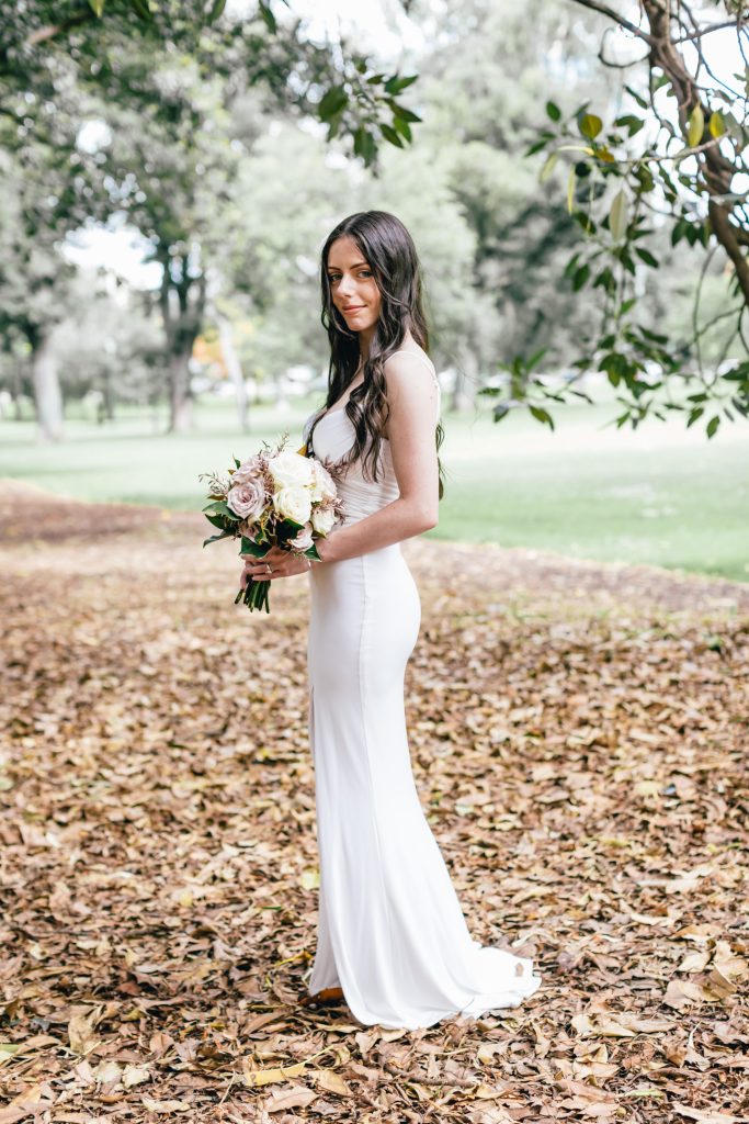 Beautiful bride posing with her roses bouquet at Fitzroy Gardens.