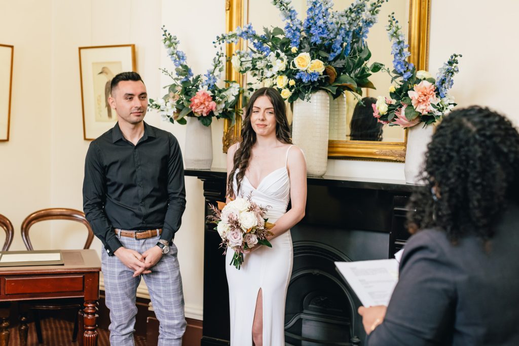 Bride, groom and wedding celebrant during ceremony at Victorian Registry Office.