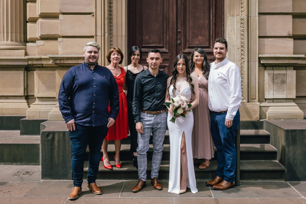 Bride and groom with their wedding guests outside Melbourne Registry Office building.