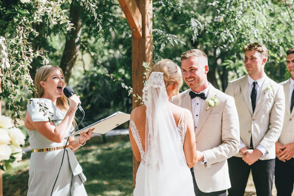 Groom smiles at bride during outdoor wedding ceremony at Ravenswood Homestead Wedding.