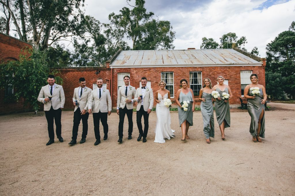Bride and groom with their fun bridal party walking during outdoor photo session at Ravenswood Homestead Wedding.