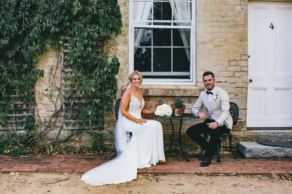 Bride and groom sit down pose in a rustic Ravenswood Homestead Wedding.