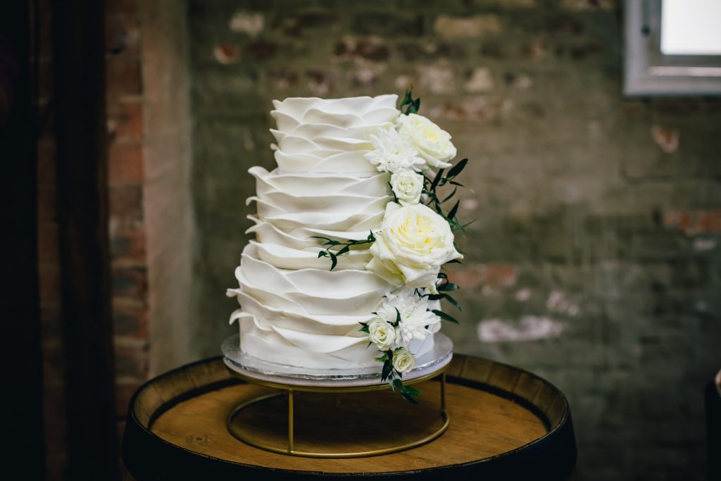 Rustic white three tier wedding cake with roses.