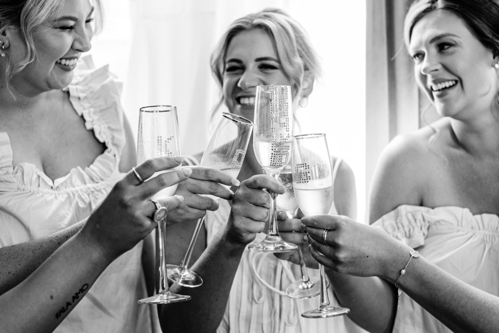 Bride and bridesmaids toast with champagne during getting ready for the wedding.