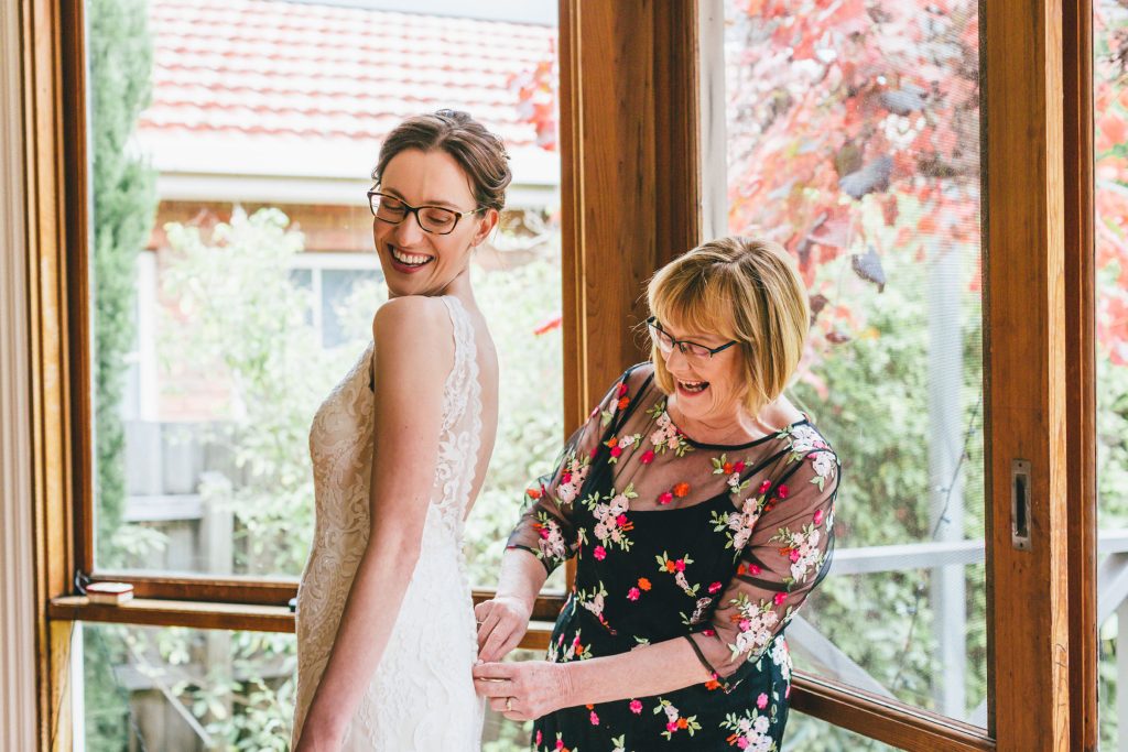 Bride with her mom helping fixing her wedding dress.