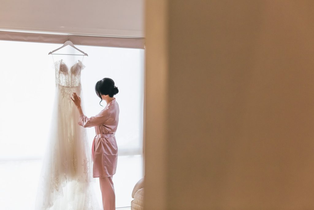 Bride touching her beautiful white wedding dress during getting ready.