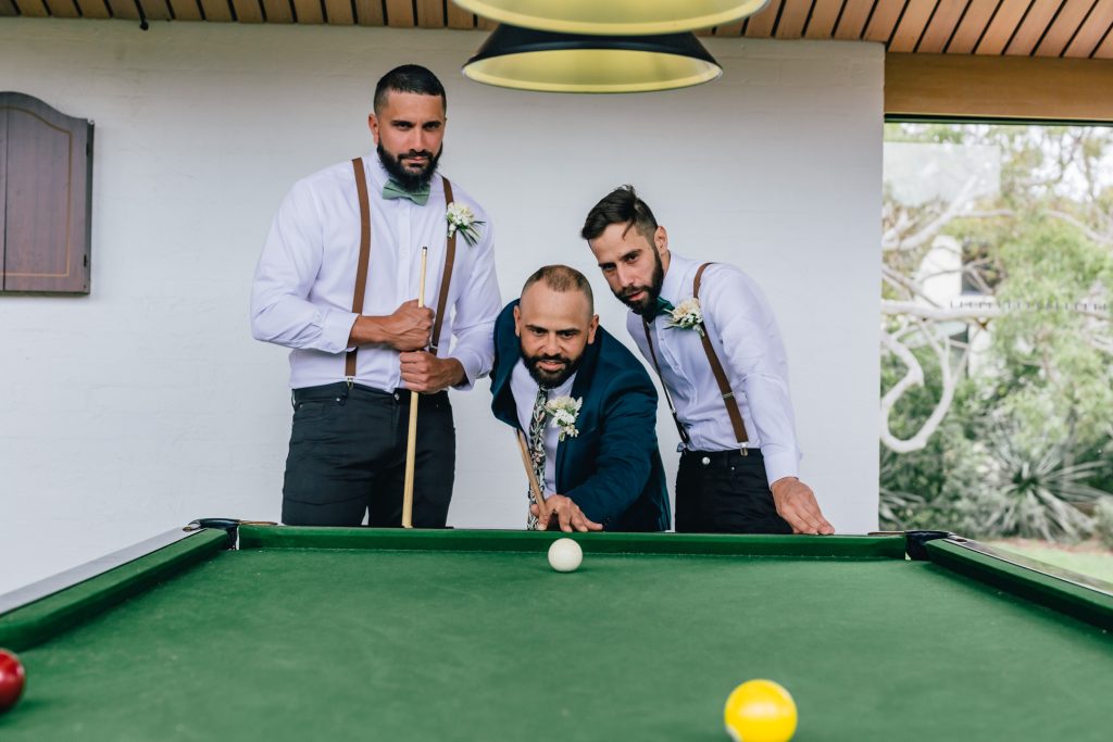 Groom and his two groomsmen playing billiards pool before his wedding ceremony.