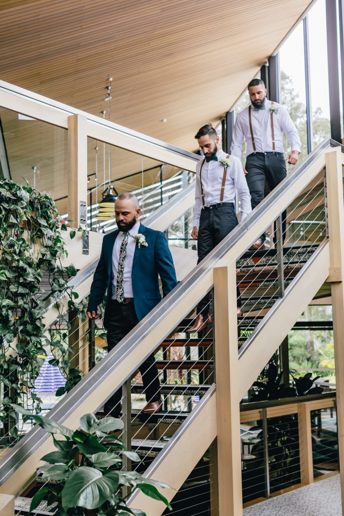 Groom and his groomsmen walking down timber stairs.