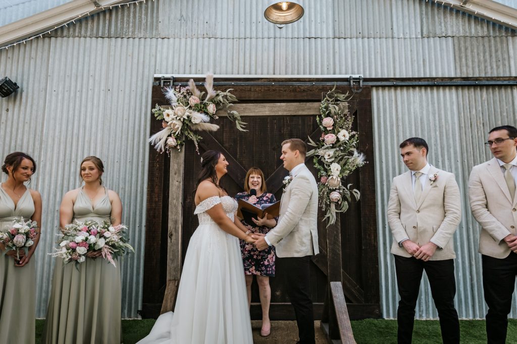 Bride and groom during wedding ceremony with their bridal party and wedding celebrant at Rocklea Farm Stonehaven.
