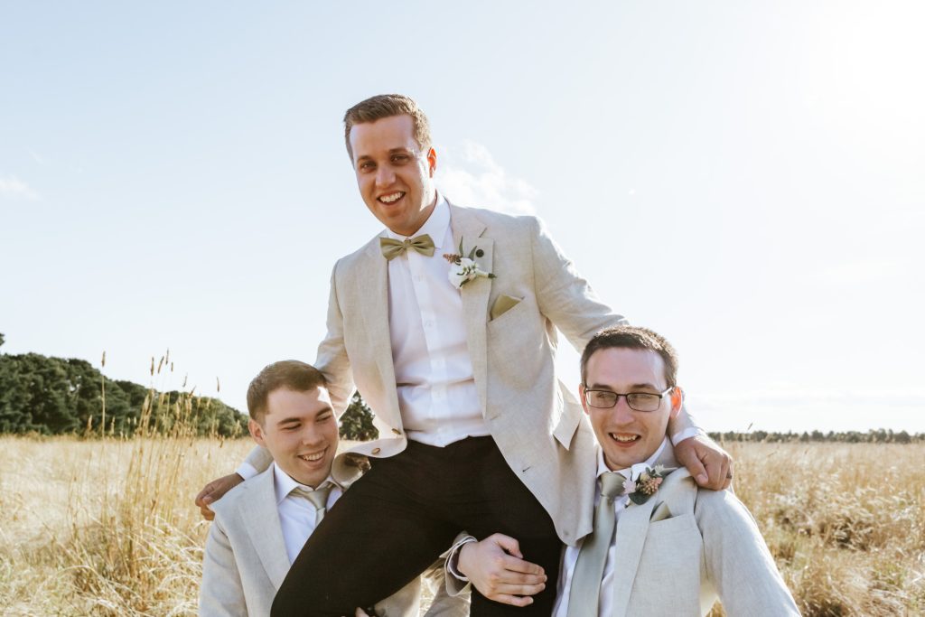 Groomsmen carrying the groom on their shoulders.