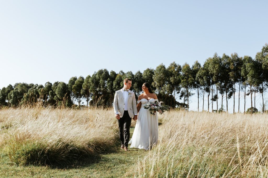 Bride and groom happily walking while holding each other hands at Rocklea Farm.