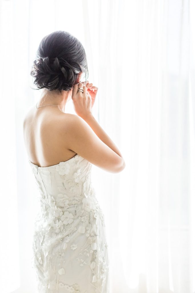 Bride fixing her earrings during getting ready.