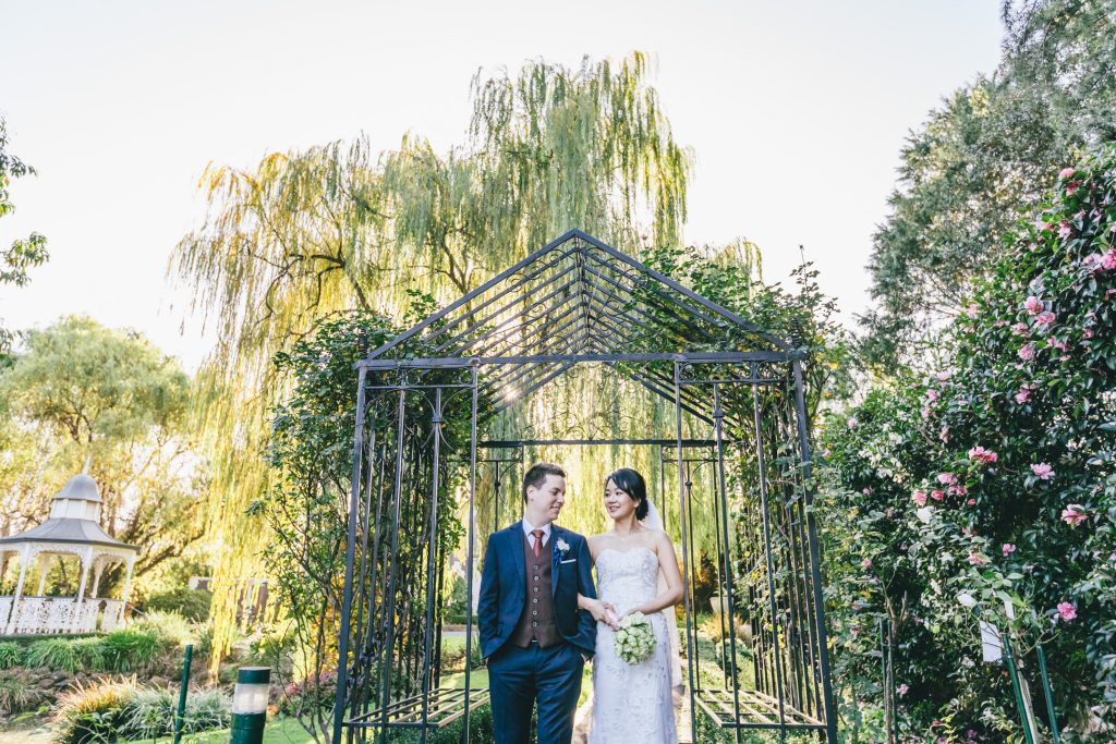 Bride and groom posing at beautiful garden arch at Ballara Receptions Eltham.